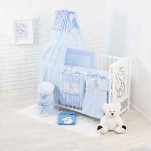 Zestaw z niebieskim baldachimem założonym na krótszym boku łóżeczka.