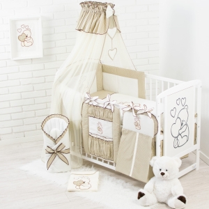 Baldachim założony na krótszym boku łóżeczka w kolorze ciemnobeżowym.