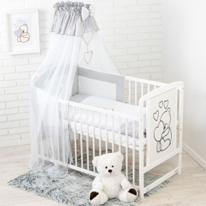 Komplettes Arrangement des Babybetts mit Accessoires und Textilien